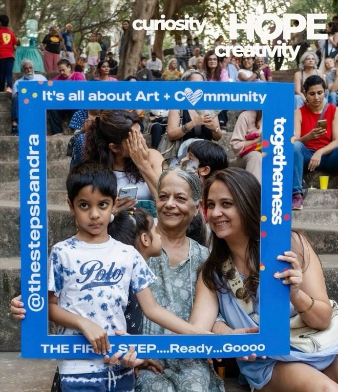 A boy, his grandmother and his mother smiling through a blue photo frame that reads It's all about Art + Community