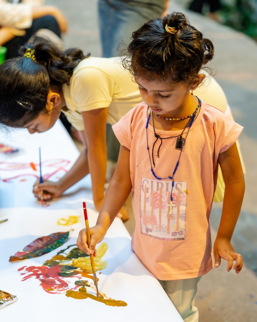 A young girl painting on a long sheet of paper at The Steps