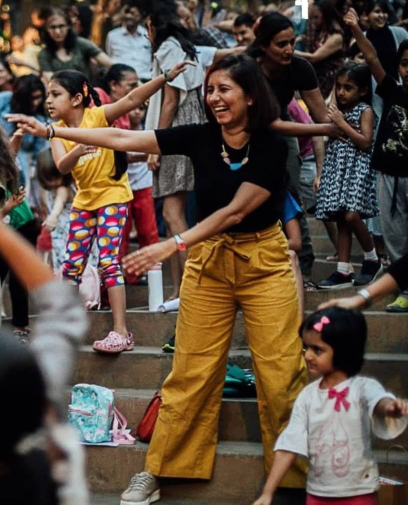 A woman dancing on the steps with children around her