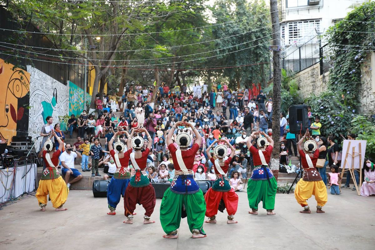 A folk dance troupe in bright costumes performing to a crowd on The Steps