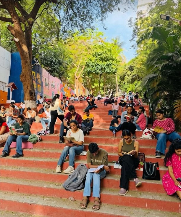 Young people sitting on the red steps, each reading a book