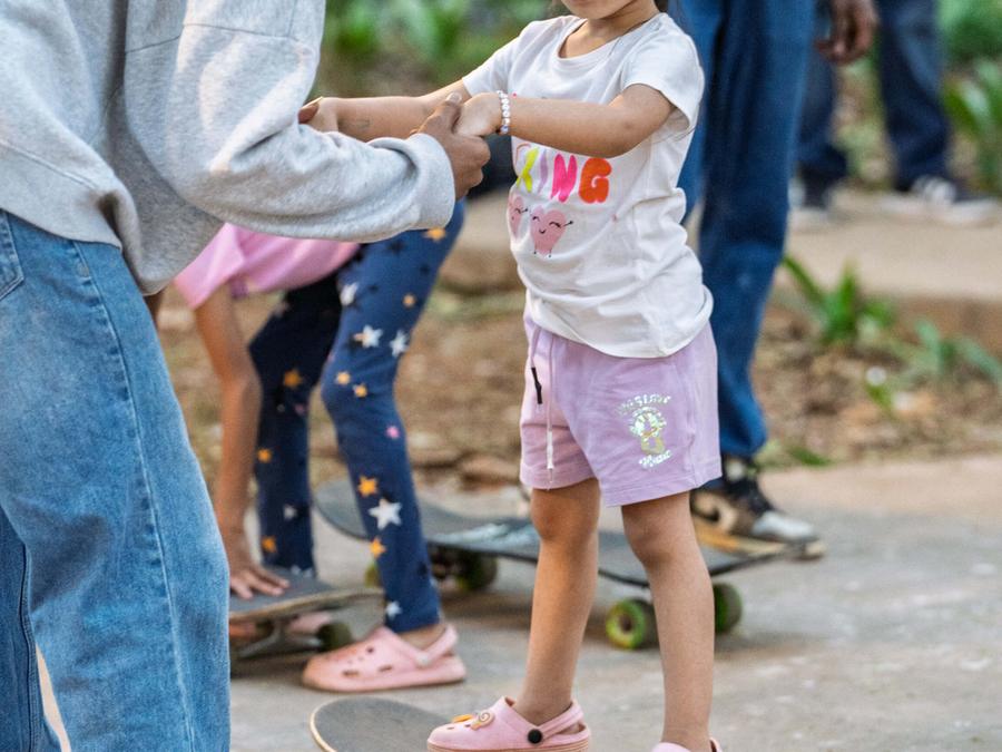 A young girl learning to skateboard with help