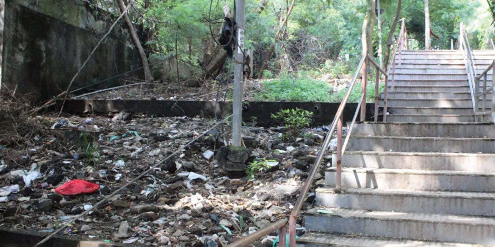 The staircase in 2017: broken steps, a rusted railing and rubbish piled beside them