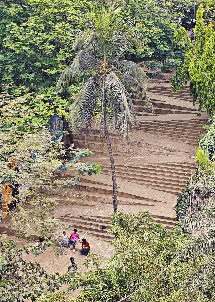 Young people sitting together on the lower landing, seen from above through palm fronds